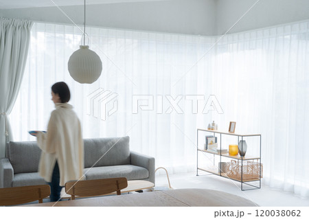 窓の広いリビングと住人の女性 窓の広いリビングと住人の女性 120038062