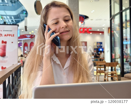 A young woman enjoys coffee while working on her laptop  120038177