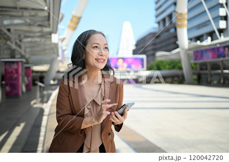 Happy senior businesswoman using smartphone in the city 120042720