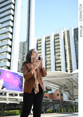 Cheerful mature businesswoman enjoying a phone conversation in front of skyscrapers Cheerful mature businesswoman enjoying a phone conversation in front of skyscrapers 120042724