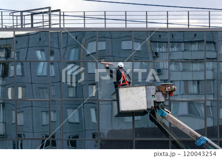 A man on a lift washes mirrored windows of a multi-story building. 120043254