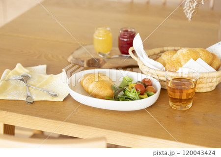 朝食　テーブルに置かれたパンとサラダ 120043424