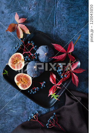 Ripe figs with red grape leaves. Autumn still life. Dark background Ripe figs with red grape leaves. Autumn still life. Dark background 120043850