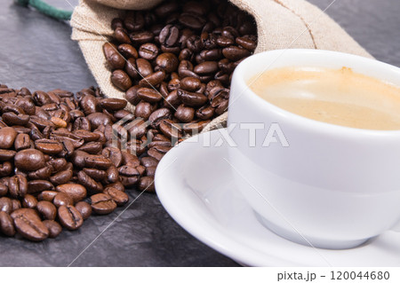 White cup of coffee and roasted fragrant dark coffee grains in bag 120044680