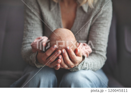 Close up mom gently cradling and rocking newborn baby in arms. Focus on hands holding baby, capturing tender, intimate moment of maternal care and love 120045811