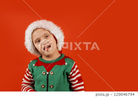Happy child with Down syndrome in Christmas scarf having fun and laughing in studio. Christmas mood. happy new year. Portrait on red background 120046794