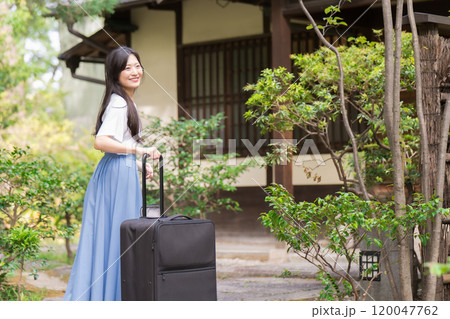 キャリーケースを引いて田舎に帰省する若い女性　旅行イメージ  120047762