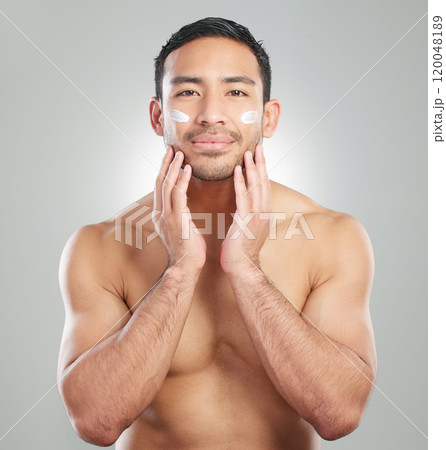 Cosmetics, man and facial cream in studio portrait for wellness, hygiene and grooming or cleaning. Male person, topless and applying product in grey background for health, smooth skin and lotion 120048189