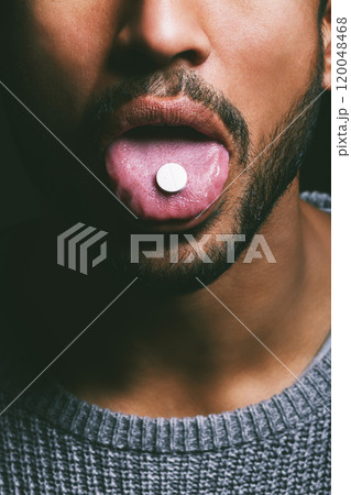 Drug, mouth and man with tablet, in studio for medication, relief or healthcare on dark background. Tongue out, addict and male person taking medical supplement, vitamin pill or substance abuse Drug, mouth and man with tablet, in studio for medication, relief or healthcare on dark background. Tongue out, addict and male person taking medical supplement, vitamin pill or substance abuse 120048468