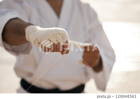 Hands, fighter and bandage wrapping fist for martial arts, training or exercise to prepare for karate match. Man tying gloves, warrior and getting ready for tournament, practice or beach workout Hands, fighter and bandage wrapping fist for martial arts, training or exercise to prepare for karate match. Man tying gloves, warrior and getting ready for tournament, practice or beach workout 120048561