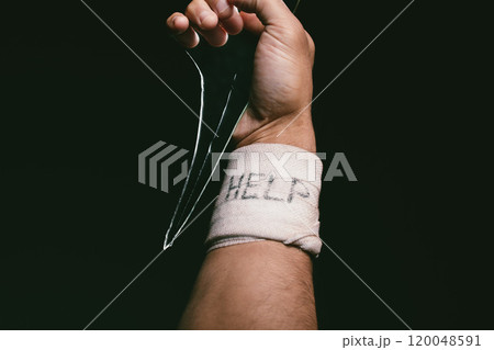 Hand, bandage and help in black background for depression, bipolar disorder and anxiety with self harm. Studio, weapon or actions of person with injury, accident and seek assistance for mental health 120048591
