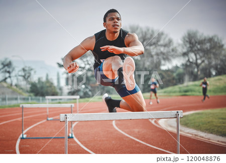 Hurdles, fitness and man running on track at stadium training for race, competition or marathon. Energy, jump and male athlete sprint by equipment for cardio workout or exercise at sports arena. 120048876