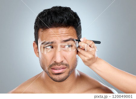 Eyebrow, pain and man with tweezers in studio for hair removal, hygiene and facial treatment. Skincare, beauty and person anxious with tool for epilation, self care and grooming on white background 120049001