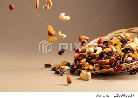 Flying dried fruits and nuts on a beige background. 120049237