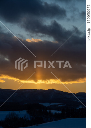 冬の山から伸びる太陽柱 120050971