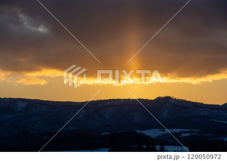 冬の山から伸びる太陽柱 120050972