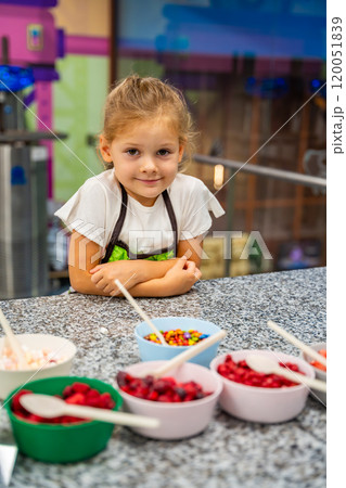 Little girl learning how to cook in a cooking class. Handmade dessert. Making chocolate candy, Child filling heart shaped mold with chocolate Little girl learning how to cook in a cooking class. Handmade dessert. Making chocolate candy, Child filling heart shaped mold with chocolate 120051839
