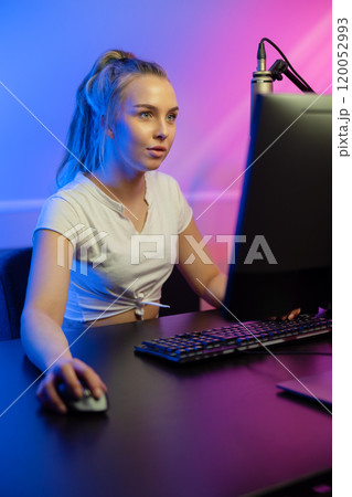 Close-up of focused professional gamer girl playing online multiplayer video game on PC 120052993