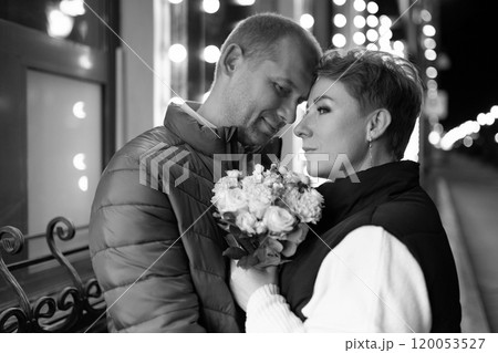 A couple walks hand-in-hand through the city at night, sharing a tender moment 120053527