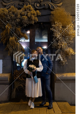 A married couple walks hand-in-hand through the city at night, stopping for a moment to look at A married couple walks hand-in-hand through the city at night, stopping for a moment to look at 120053589
