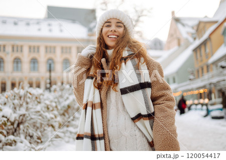 Beautiful woman playing with snow on winter street. Fashion young woman in winter park. Christmas. 120054417