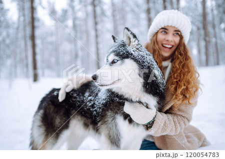 Beautiful young woman plays with her dog in winter forest. First snow Friendship. Outdoor recreation Beautiful young woman plays with her dog in winter forest. First snow Friendship. Outdoor recreation 120054783