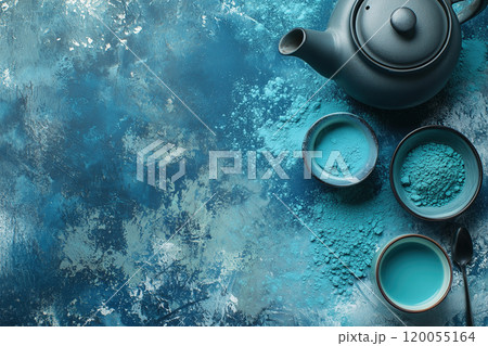 Ceramic teapot and bowls with blue matcha powder on a textured blue surface in a cozy kitchen 120055164