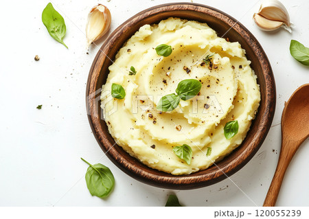 Creamy mashed potatoes with garlic and fresh basil ready to serve in a rustic wooden bowl on a light Creamy mashed potatoes with garlic and fresh basil ready to serve in a rustic wooden bowl on a light 120055239