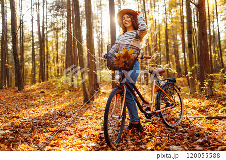 Happy active young woman on bike in autumn park at sunset. Concept of people, recreation, active lifestyle. 120055588