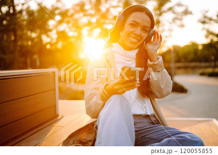 Young woman listens to music, audiobook or podcast. Communication in social networks. Lifestyle. 120055855