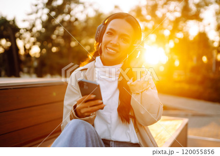 Young woman listens to music, audiobook or podcast. Communication in social networks. Lifestyle. Young woman listens to music, audiobook or podcast. Communication in social networks. Lifestyle. 120055856