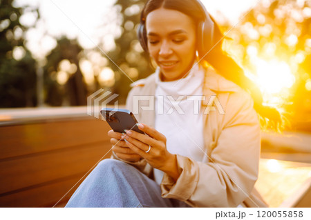 Young woman listens to music, audiobook or podcast. Communication in social networks. Lifestyle. 120055858
