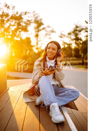 Young woman listens to music, audiobook or podcast. Communication in social networks. Lifestyle. 120055859