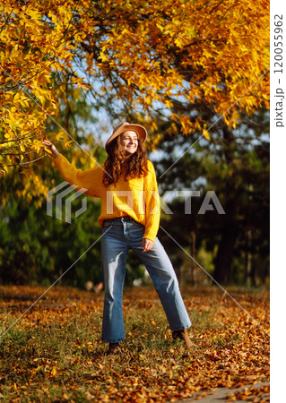 Young woman in a yellow sweater and jeans resting in nature. Fashion, style concept. People, lifestyle. 120055962