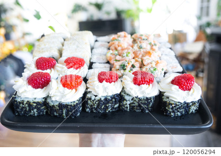 Delivery of sushi and rolls set is hold in hand in the interior modern kitchen of house 120056294