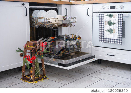 A lot of dirty dishes in the dishwasher in the festive kitchen. Helping the hostess, economy and ecology. Cleaning in the kitchen for the holidays of Christmas and New Year, after the feast and guests 120056840