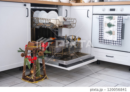 A lot of dirty dishes in the dishwasher in the festive kitchen. Helping the hostess, economy and ecology. Cleaning in the kitchen for the holidays of Christmas and New Year, after the feast and guests 120056841
