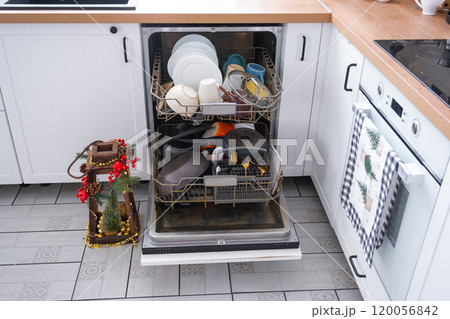 A lot of dirty dishes in the dishwasher in the festive kitchen. Helping the hostess, economy and ecology. Cleaning in the kitchen for the holidays of Christmas and New Year, after the feast and guests 120056842