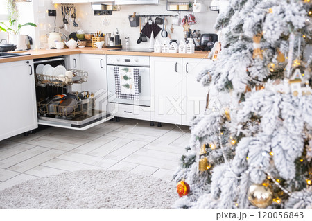 A lot of dirty dishes in the dishwasher in the festive kitchen. Helping the hostess, economy and ecology. Cleaning in the kitchen for the holidays of Christmas and New Year, after the feast and guests 120056843