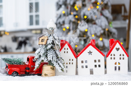Key on Christmas tree and tiny house with a red roof with Christmas decor in red retro car on table . Gift for New Year. Insurance, moving to new house, mortgage, rent and real estate 120056860