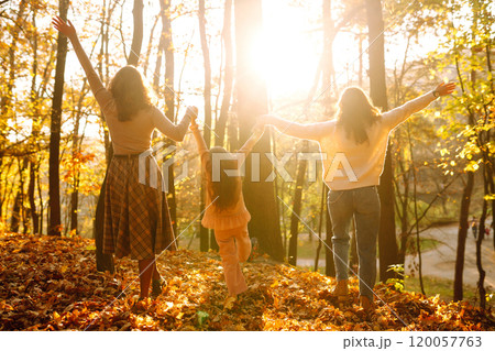 The homosexual family playing with her daughter in the autumn forest. The adventure is more fun. 120057763