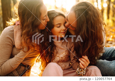 The homosexual family playing with her daughter in the autumn forest. The adventure is more fun. 120057764