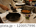 シェフがイカスミパエリアを取り分ける 120057996