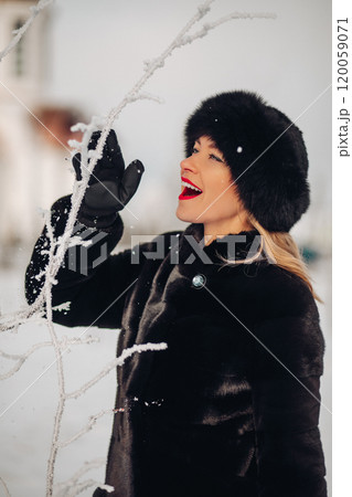 A beautiful woman in a black fur coat and a black 120059071