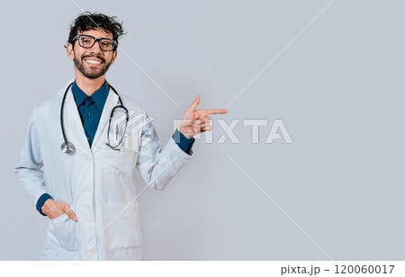 Young doctor pointing a promotion with his finger. Handsome doctor pointing at advertising space isolated. Happy doctor pointing right with finger Young doctor pointing a promotion with his finger. Handsome doctor pointing at advertising space isolated. Happy doctor pointing right with finger 120060017
