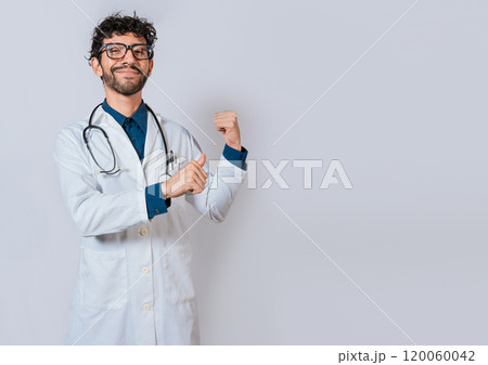 Smiling doctor pointing back isolated. Doctor pointing back with his thumbs, recommending a product. Smiling doctor pointing back isolated. Doctor pointing back with his thumbs, recommending a product. 120060042