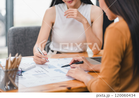 Two businesspeople or an accountant team are analyzing data charts, graphs, in order to prepare a statistical report and discuss financial data in an office. 120060434