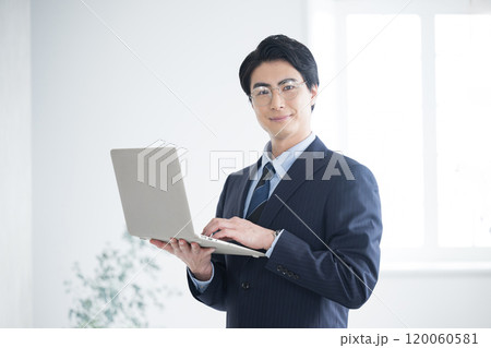 税理士、会計士、コンサルタントの士業などパソコンを持ってカメラ目線の若いビジネスマン 税理士、会計士、コンサルタントの士業などパソコンを持ってカメラ目線の若いビジネスマン 120060581