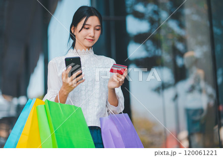A woman is shopping and using her phone to pay for her purchases 120061221