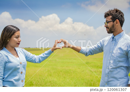 Happy couple making a heart shape with their hands, couple in love in the field making a heart shape with hands, beautiful couple in the field making a heart shape with hands Happy couple making a heart shape with their hands, couple in love in the field making a heart shape with hands, beautiful couple in the field making a heart shape with hands 120061307
